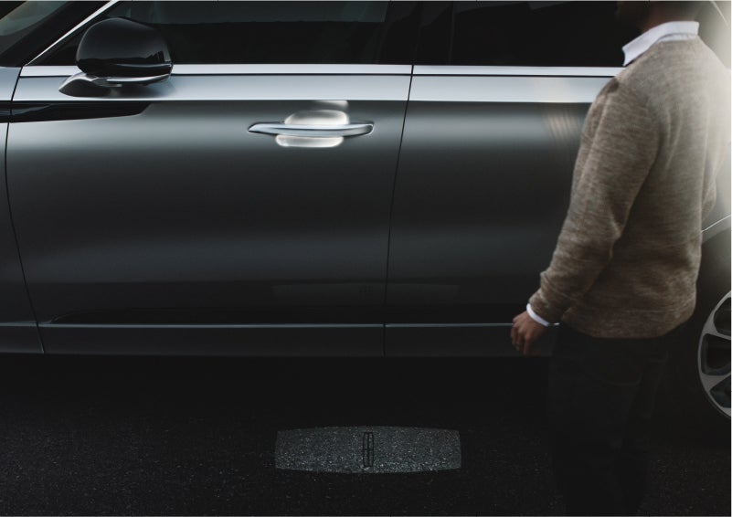 A person approaches a 2023 Lincoln Aviator® Grand Touring as the Lincoln Embrace sequence of welcome lighting illuminates | John Vance Auto Group in Guthrie OK