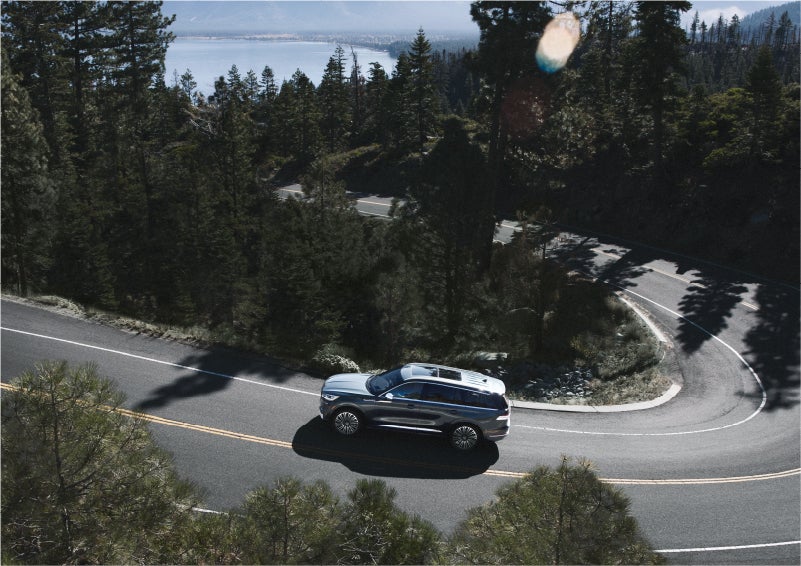 A 2023 Lincoln Aviator® SUV is being driven on a winding mountain road | John Vance Auto Group in Guthrie OK